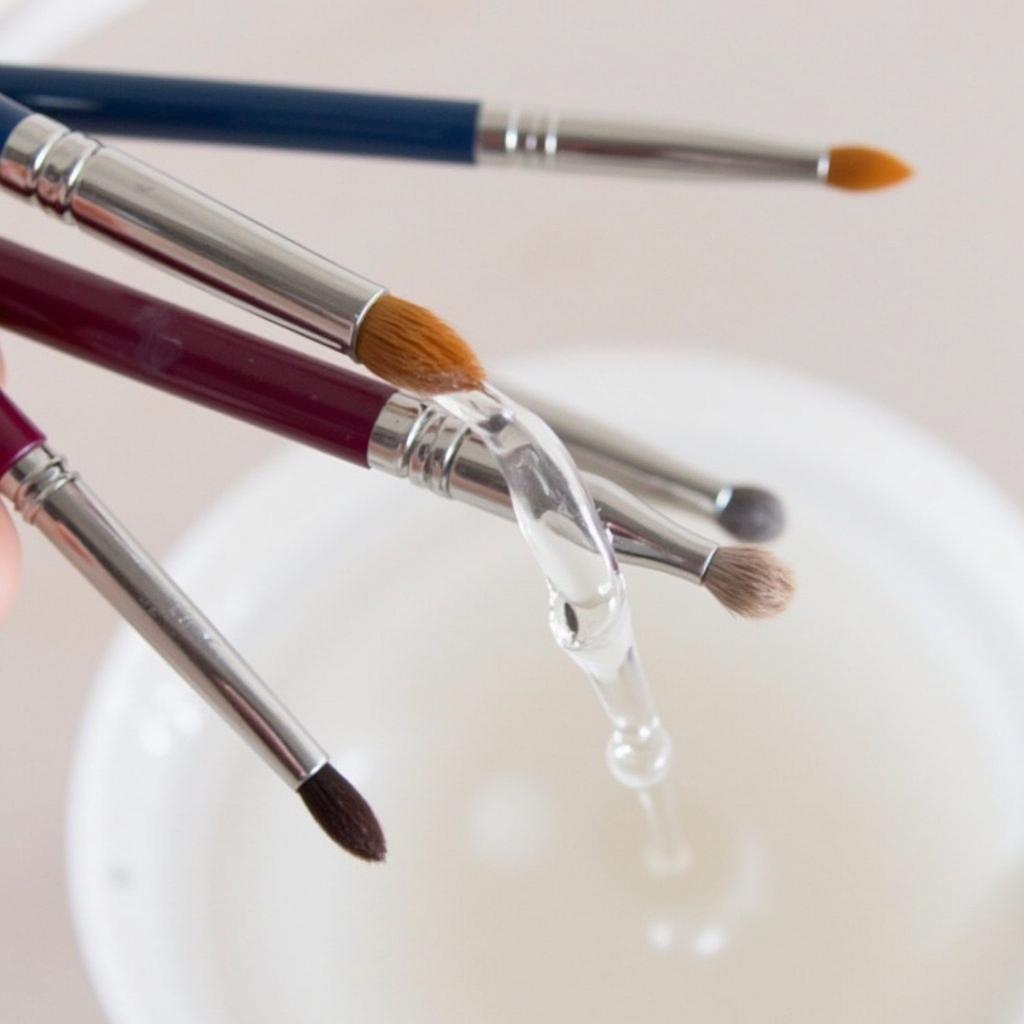 Cleaning nail art brushes with brush cleaner to maintain their shape and quality.