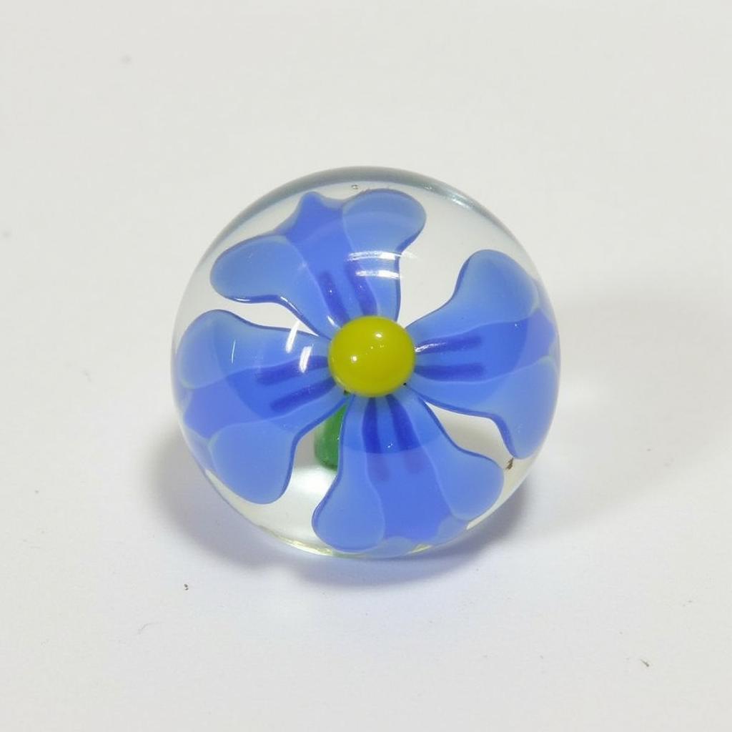 A small, intricate glass flower paperweight, a perfect example of glass art flowers.