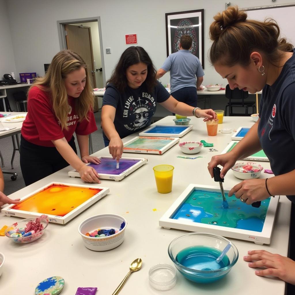 Students engaged in a resin art class, pouring resin and adding pigments.